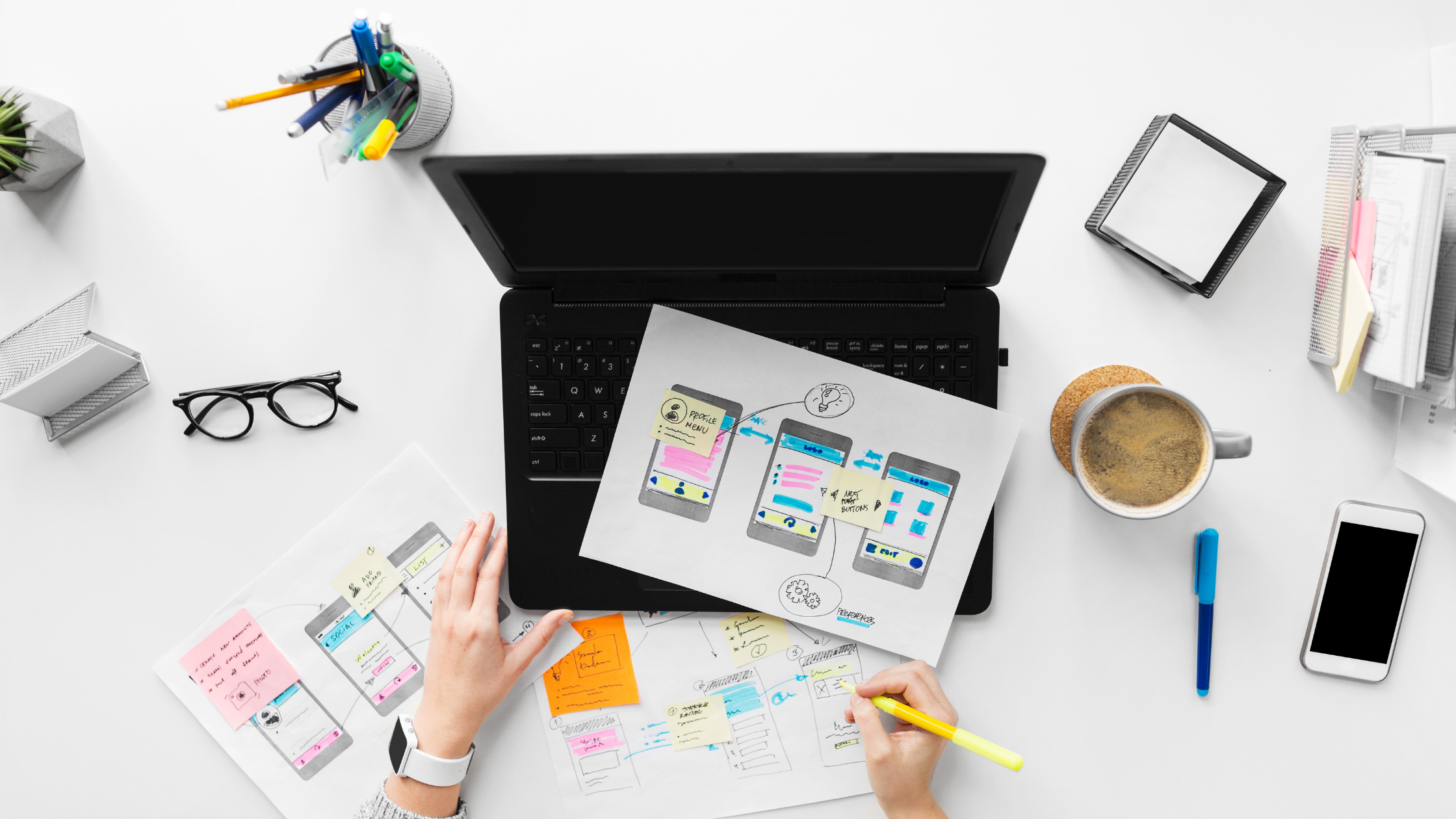 Overhead view of person working on a drawing of mobile website layouts.