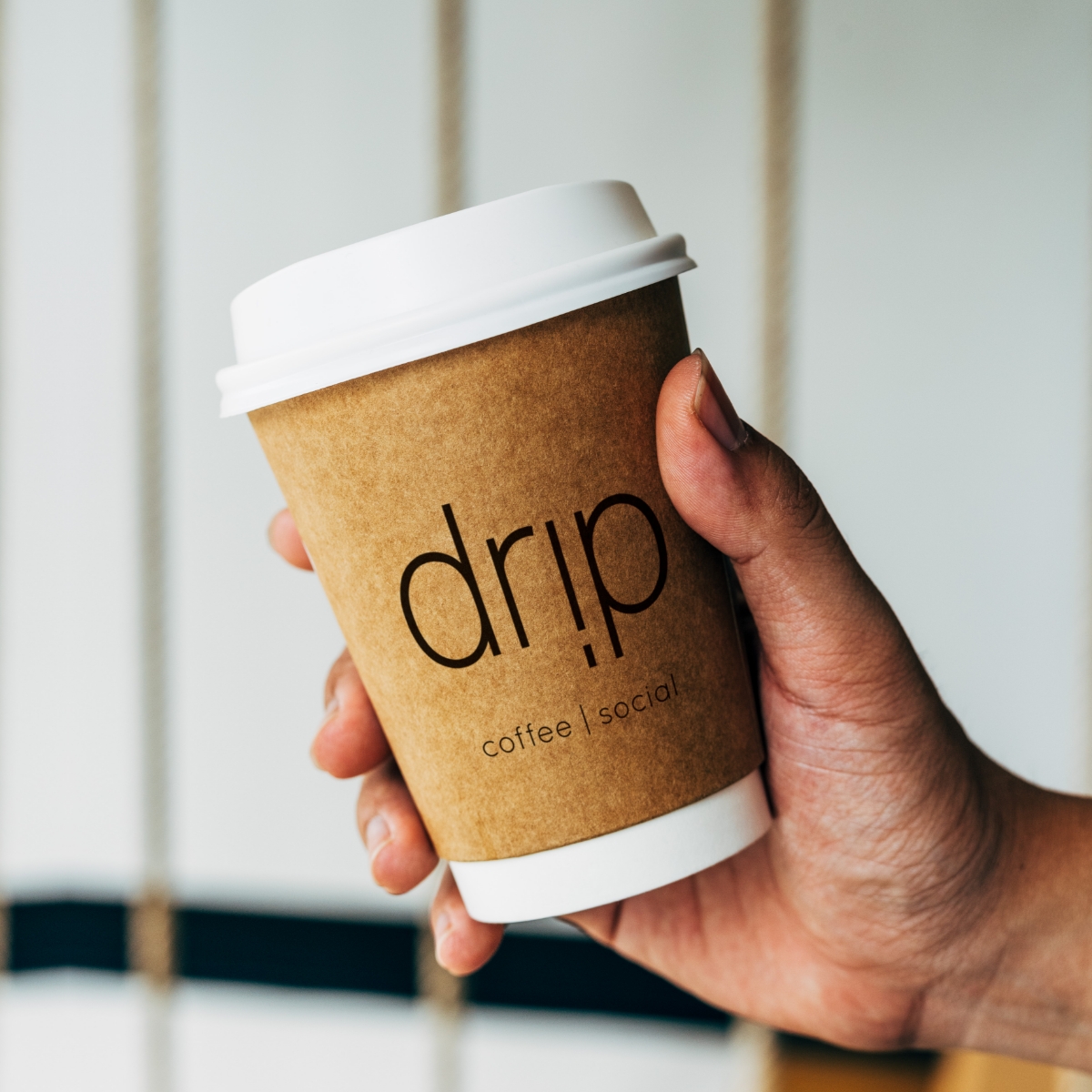 Logo Design for Drip Coffee. Handing holding a Drip branded to-go coffee cup.